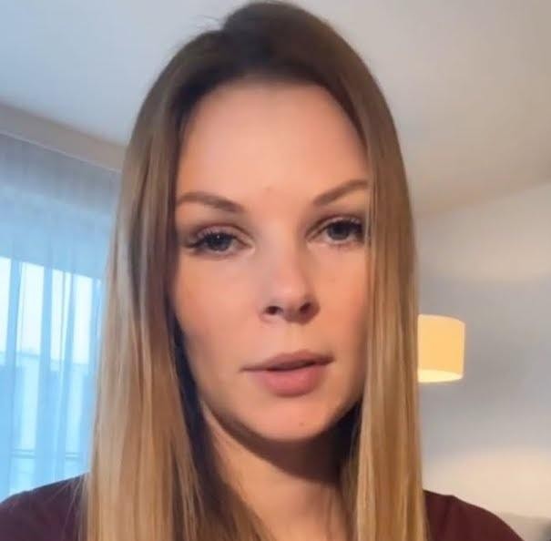 Małgorzata Tomaszewska podczas prowadzenia programu telewizyjnego, z uśmiechem i mikrofonem w dłoni, w dynamicznej pozie w studiu TV.