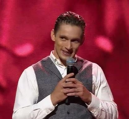 Filip Gurłacz w dynamicznej pozie tanecznej na scenie, podczas występu w programie rozrywkowym.