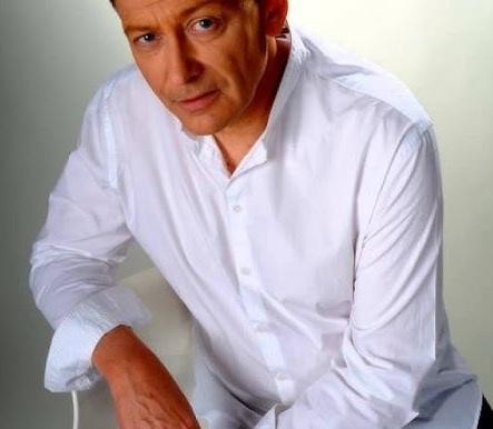 Alt: Jacek Borkowski przygotowujący posiłek w domowej kuchni, uśmiechnięty i zrelaksowany.