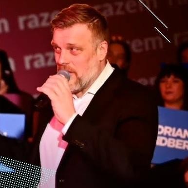 Adrian Zandberg podczas wystąpienia publicznego, z widownią w tle.