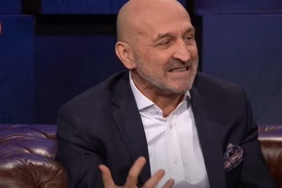 Kazimierz Marcinkiewicz w stroju bokserskim, w ringu, podczas charytatywnej walki bokserskiej, z publicznością w tle.