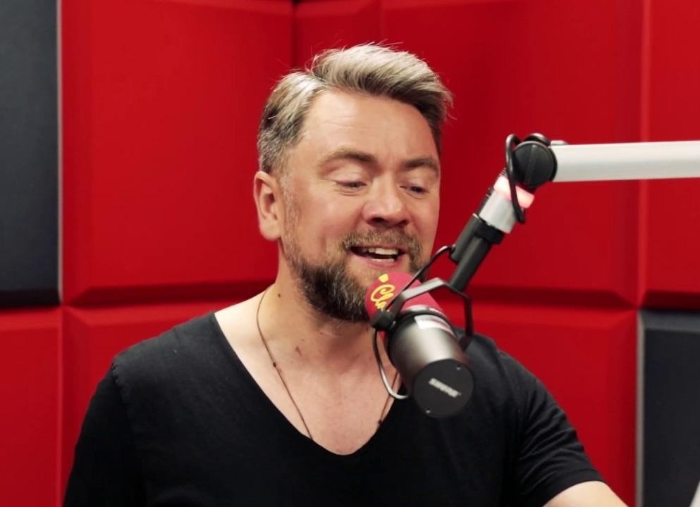 Kuba Badach w trakcie emocjonującego występu na żywo, śpiewający do mikrofonu, z dynamicznym oświetleniem scenicznym.