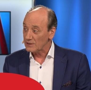 Dariusz Szpakowski w ferworze komentowania meczu piłkarskiego, z widocznym stadionem w tle, ukazujący jego pasję i zaangażowanie.