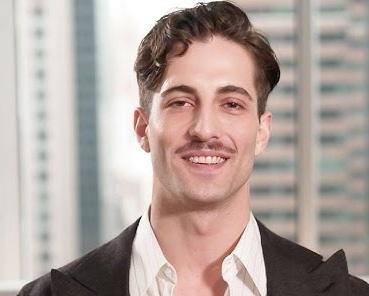 Damiano David, ujęcie od pasa w górę, w swobodnym, ale stylowym ubraniu, z intensywnym spojrzeniem, na tle sugerującym studio nagraniowe lub przestrzeń artystyczną.