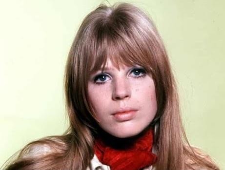 Dynamiczny portret Marianne Faithfull na scenie w późnych latach 70., z intensywnym wyrazem twarzy, dramatycznym oświetleniem i rozmytym tłem.